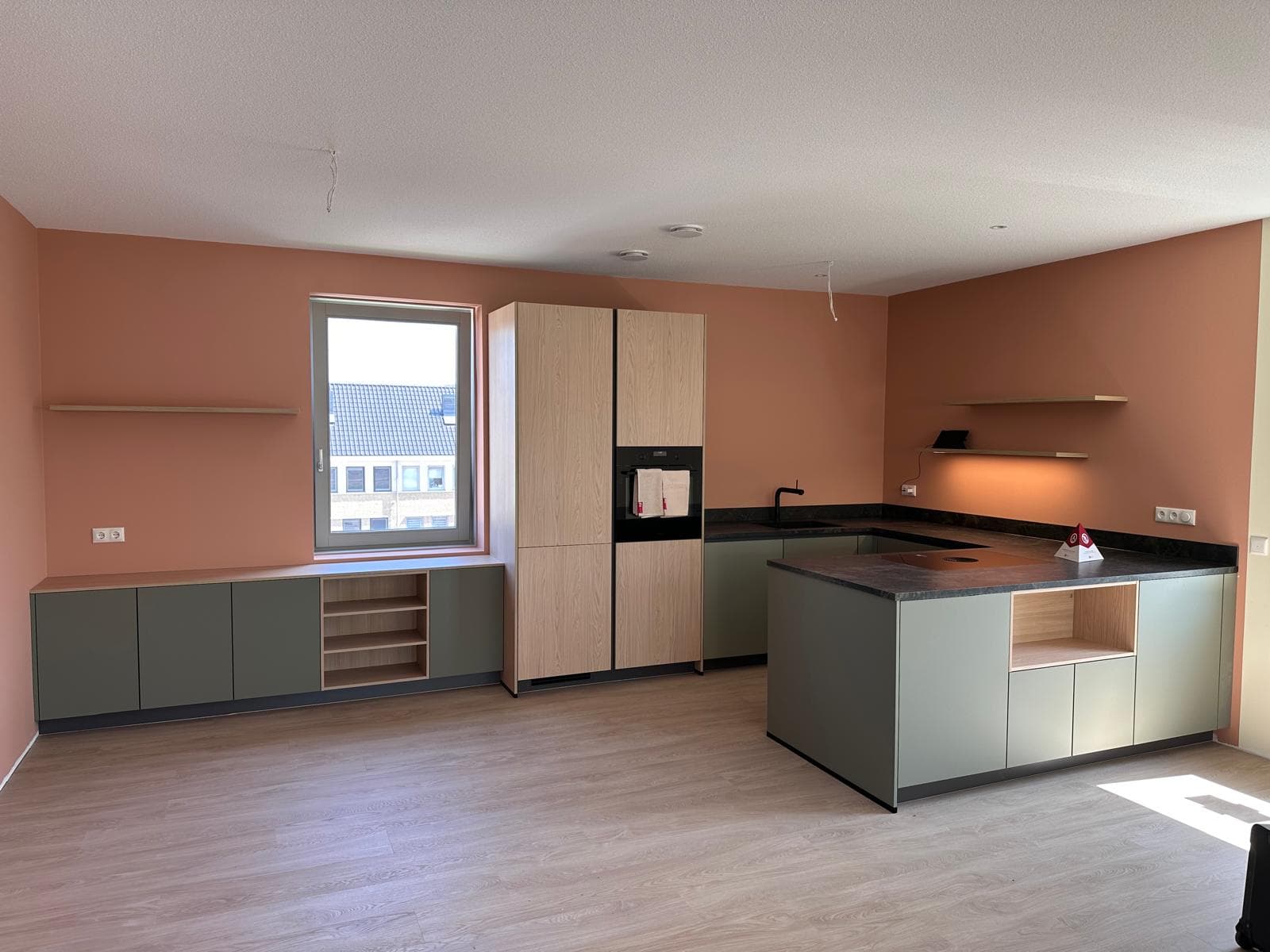 Olijfgroene keuken tegen een terracotta gekleurde wand