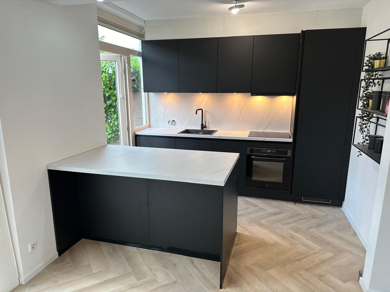 Zwarte keuken met doorlopende marmeren achterwand